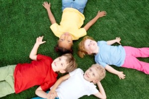children laying on artificial grass looking at sky