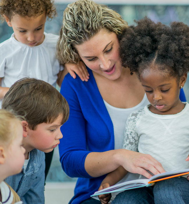 female teacher reading to group of children