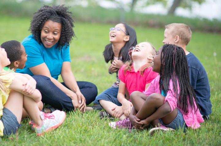 A group of children laughing in the grass