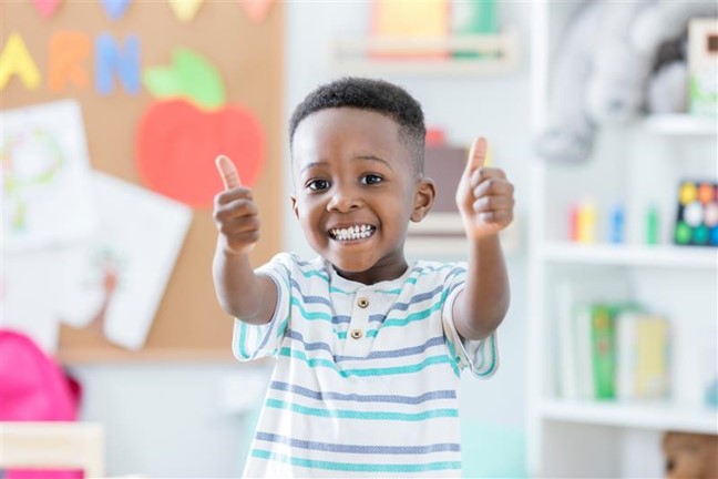 Smiling young boy enthusiastically giving two thumbs up